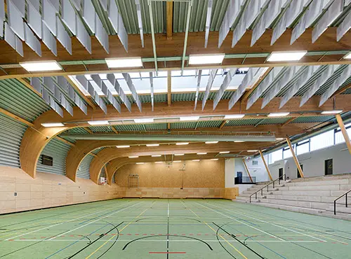 Urheiluhallin katon alapuolella riippuvat äänenvaimennuslevyt laskevat melutasoa ja vähentävät kaiuntaa.